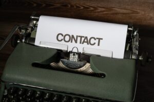 An old fashioned typewriter with a piece of paper saying CONTACT on it