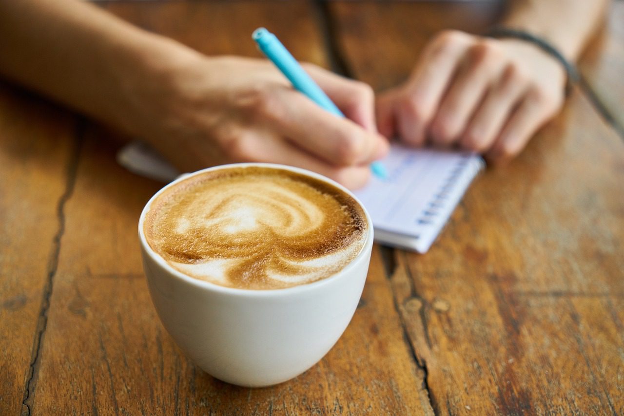 A cup of coffee and someone (a lawyer maybe?) writing on a notepad